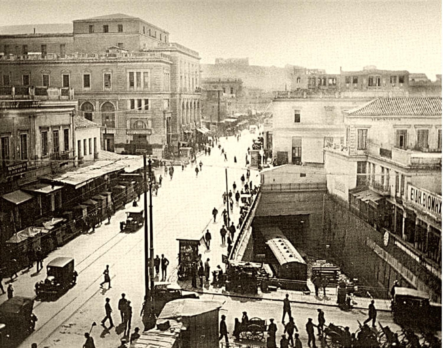 1928: Ο πρώτος υπόγειος σταθμός της Ομόνοιας, Αθηνάς & Λυκούργου. Πίσω του το δημαρχείο και, απέναντι, στην πλατεία, το Δημοτικό Θέατρο.